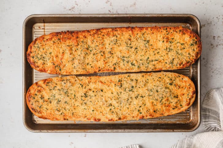 Garlic bread in oven on a rimmed baking pan, after baking.