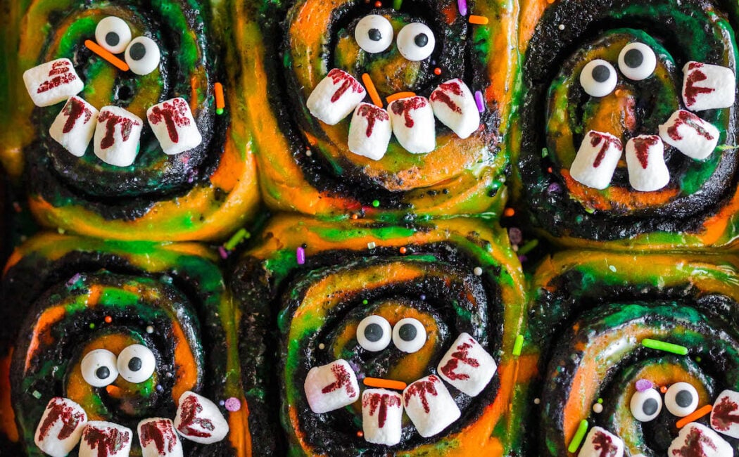 Halloween cinnamon rolls in an orange baking pan.