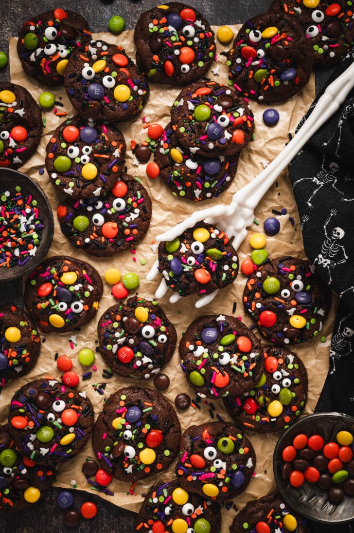 A spread of Halloween cookies with a skeleton hand lifting up one cookie.