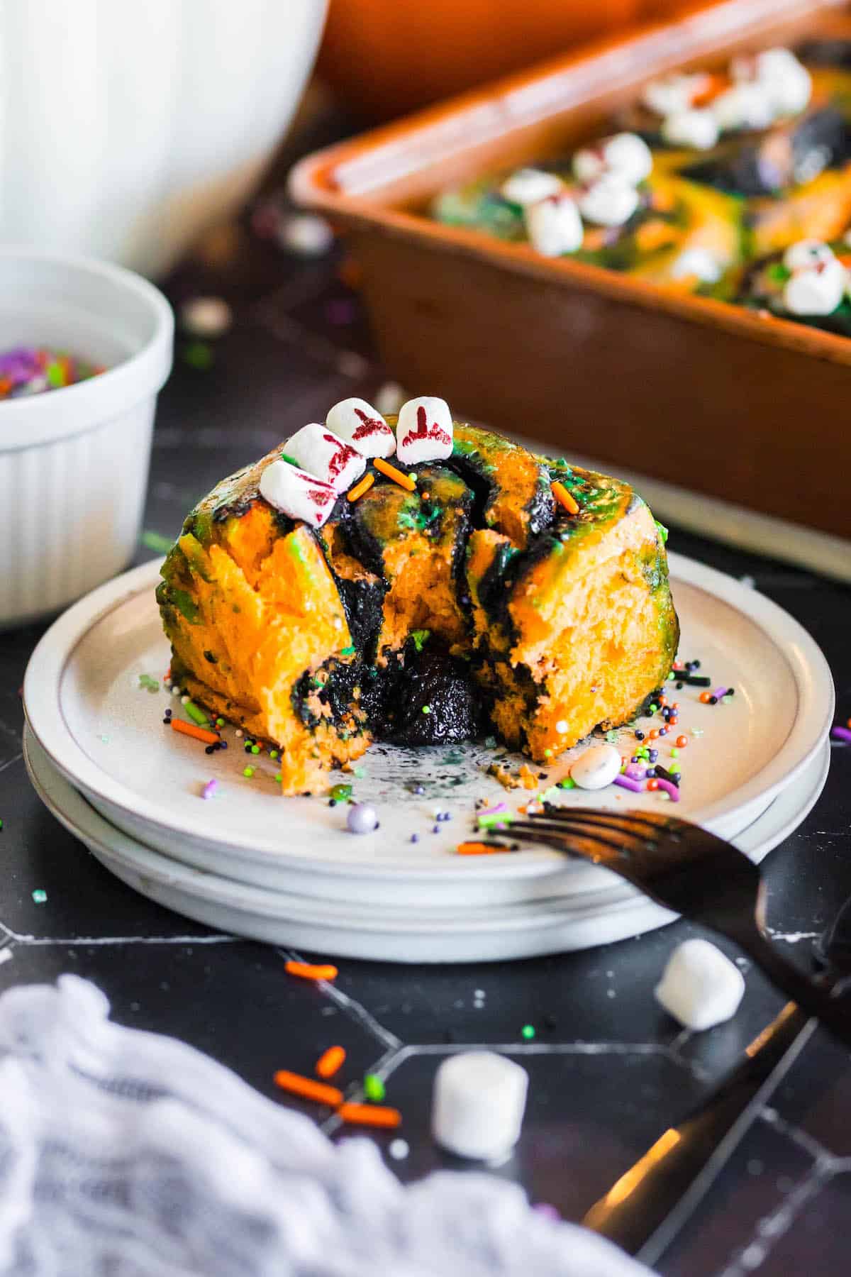 A Halloween cinnamon roll on a white plate.