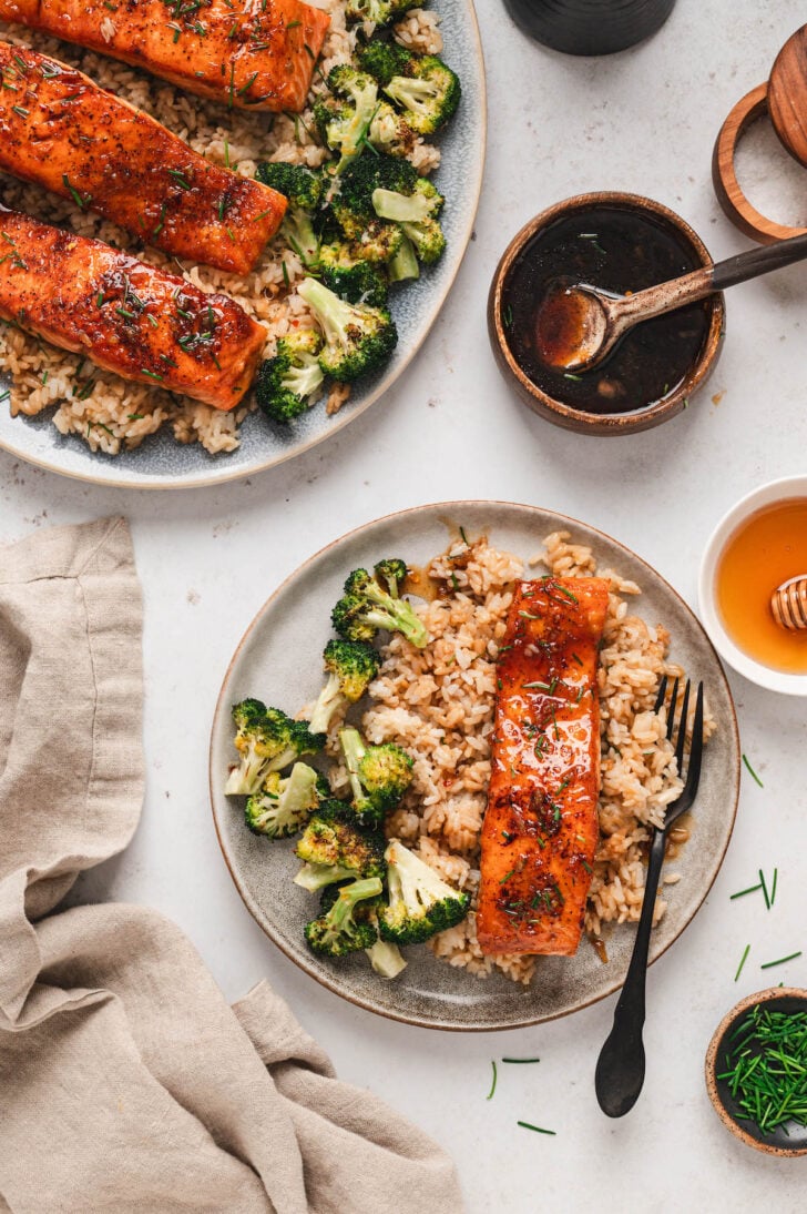 A piece of honey garlic glazed salmon on a plate, served over rice and broccoli.