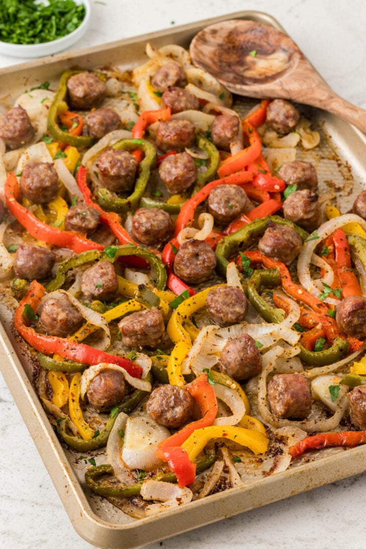 Sheet pan sausage and peppers on a light surface.