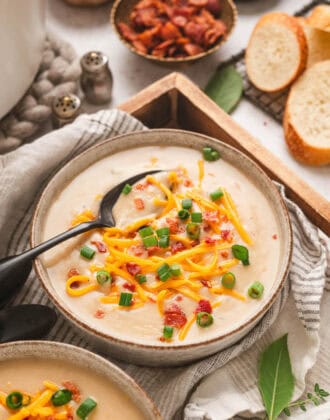 A bowl of easy potato soup topped with bacon, green onions and shredded cheese.