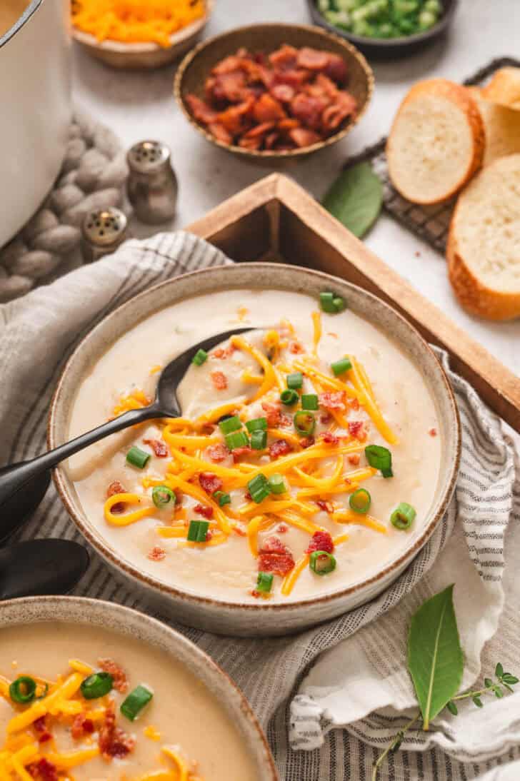 A bowl of easy potato soup topped with bacon, green onions and shredded cheese.