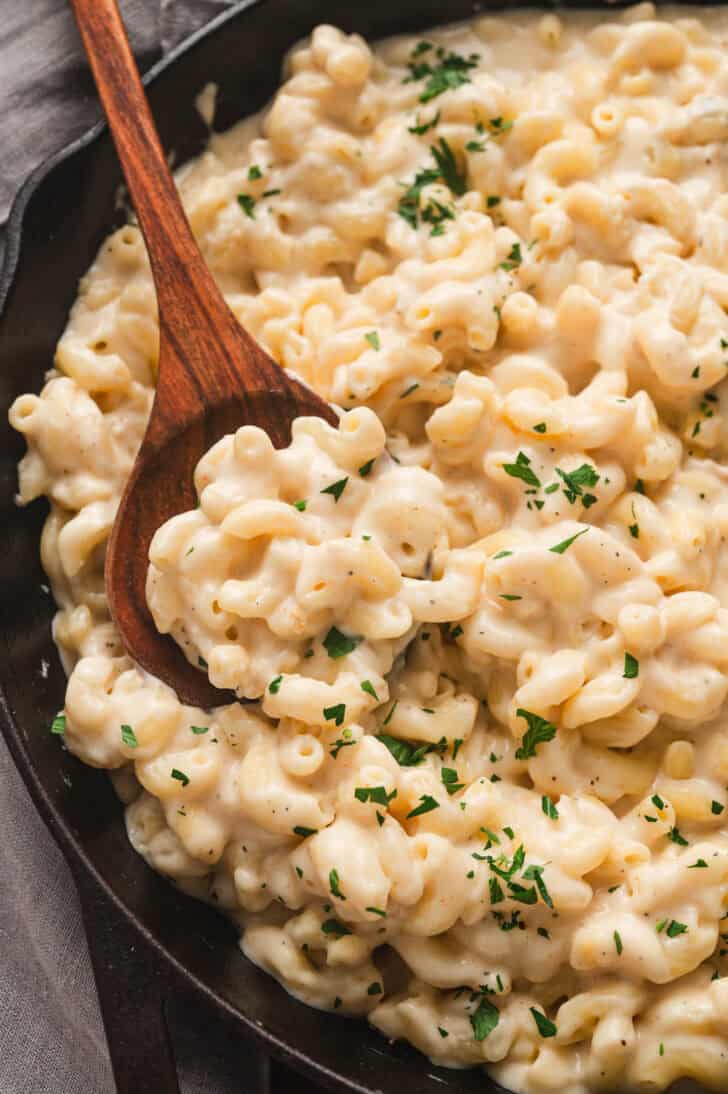 A wooden spoon stirring stovetop mac and cheese.