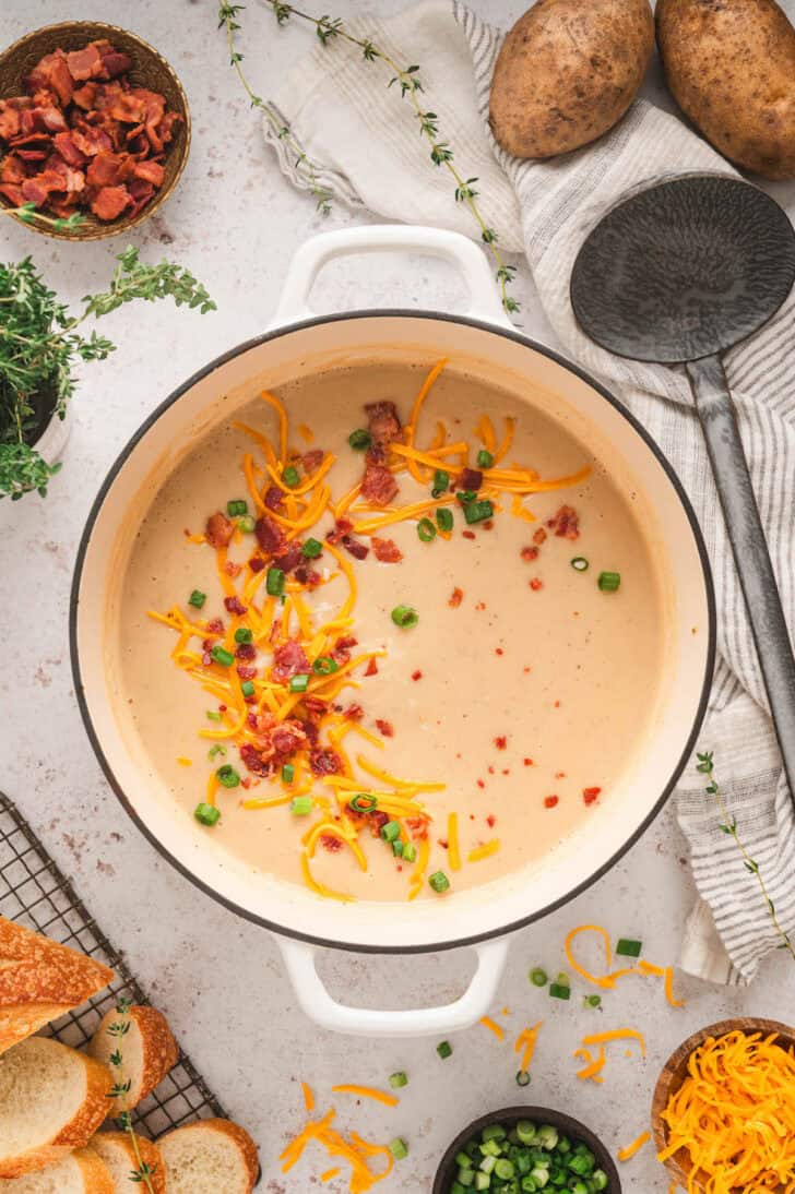 A pot of easy potato soup with chicken broth, topped with bacon, green onions and shredded cheese.