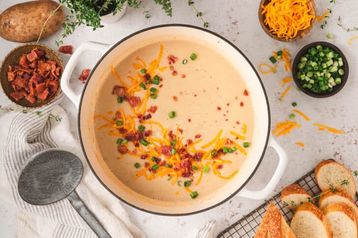 A pot of easy potato soup topped with bacon, cheese and green onions.