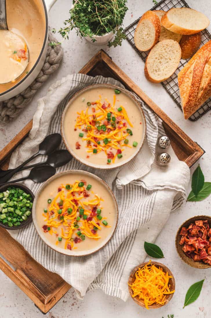 Bowls of simple potato soup recipe topped with bacon, green onions and shredded cheese.