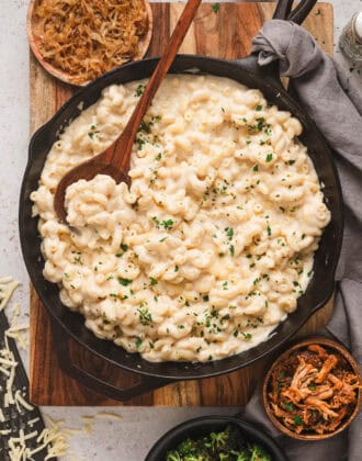 Stovetop mac and cheeses in a cast iron skillet, surrounded by various mix-in ingredients.