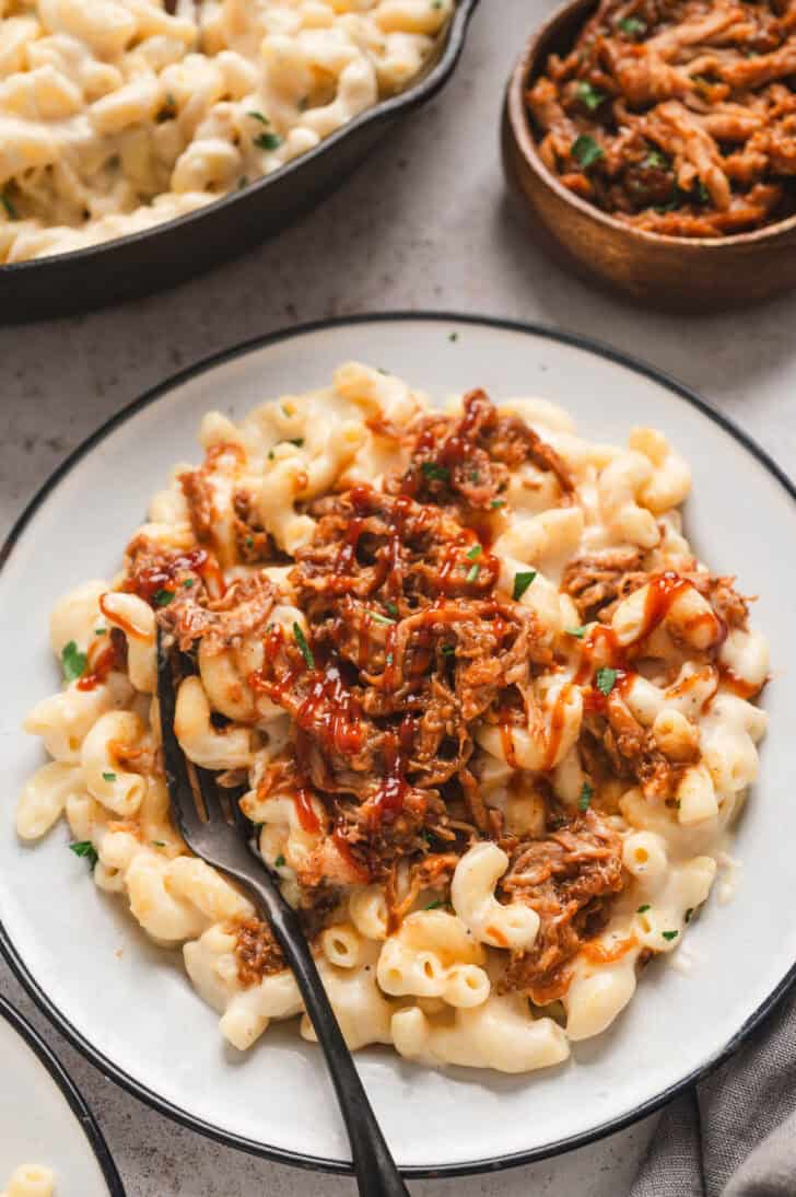 A plate of creamy stovetop mac and cheese with bbq pulled pork on top.