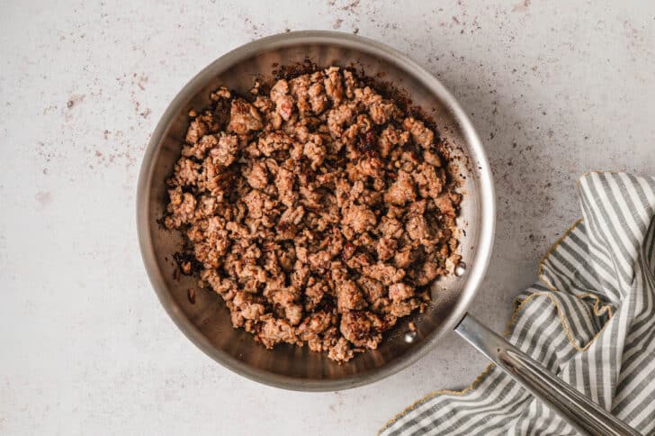 Ground sausage cooking in a skillet.