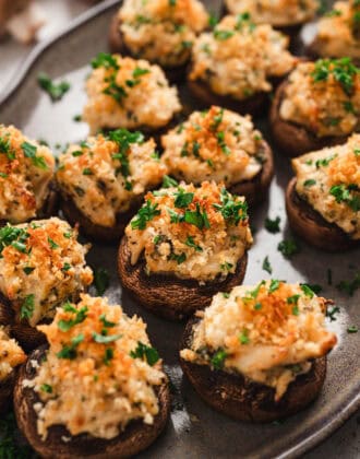 Crab stuffed mushrooms on a gray platter.