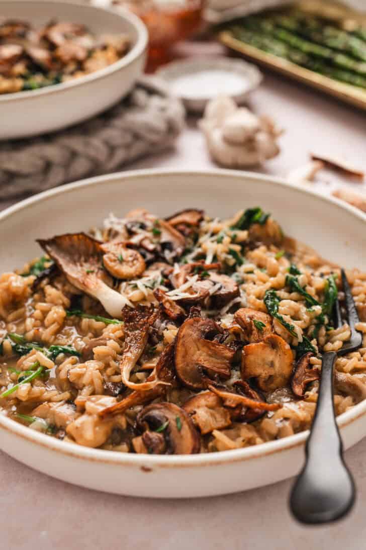 A bowl of gourmet mushroom risotto with a black fork in it.