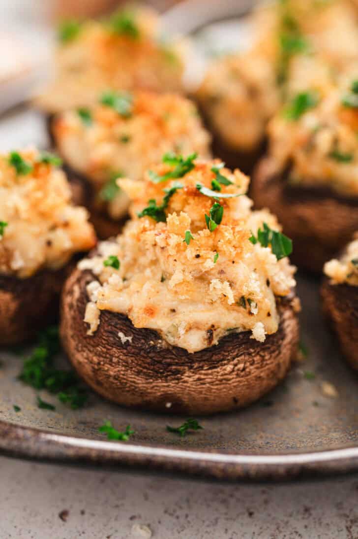 A crab stuffed mushroom recipe on a gray platter.