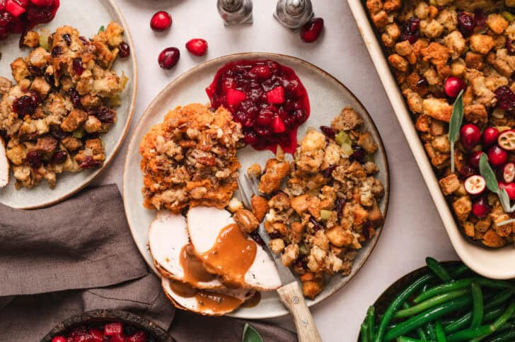 A holiday dinner plate with turkey, gravy, stuffing, cranberry sauce and make ahead sweet potato casserole.