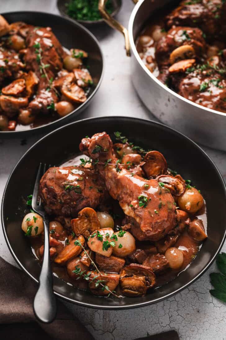 A black bowl filled with chicken co au vin.