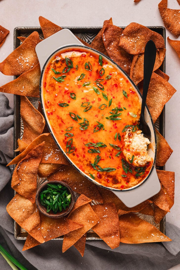 A dish of crab rangoon dip on a tray with wonton chips.