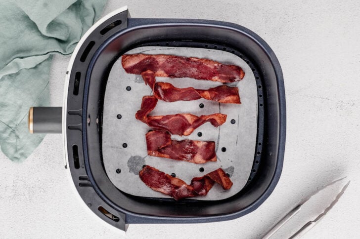 Cooked turkey bacon in air fryer basket.