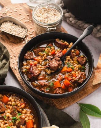 A bowl of a beef barley soup recipe with a spoon in it.