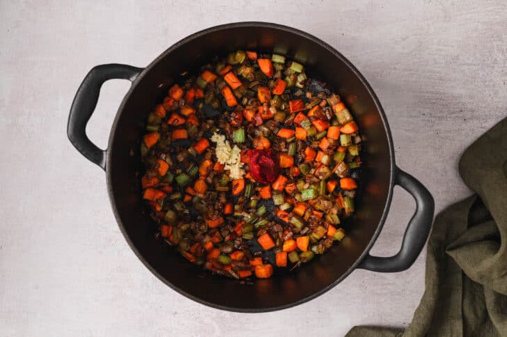 Mirepoix and tomato paste and garlic being browned in a Dutch oven.