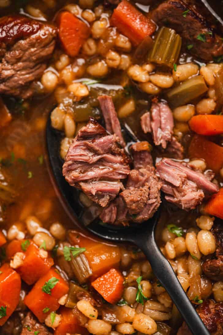 Closeup shot of a recipe for beef barley soup, showing the meat falling apart.