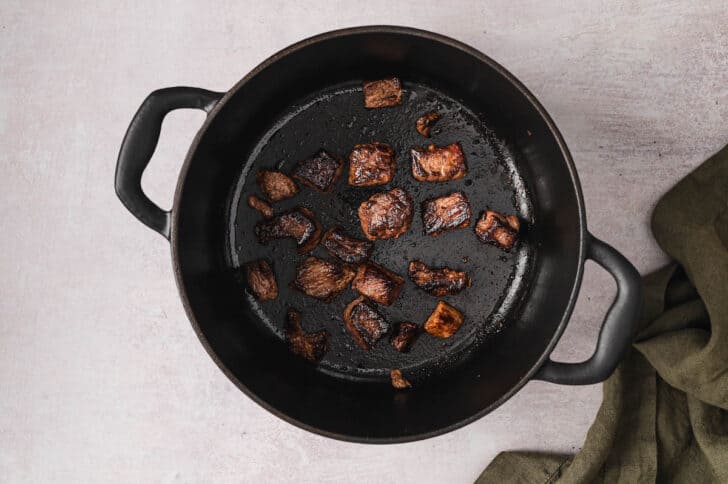 Meat being browned in a Dutch oven.