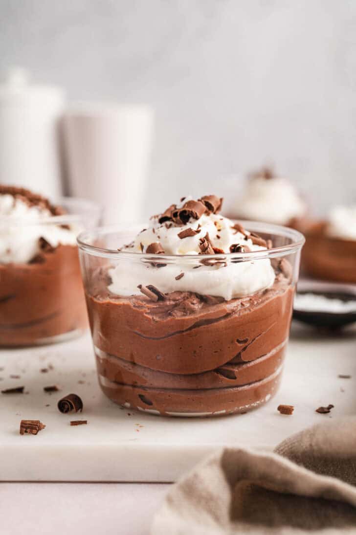 Chocolate mouse cups garnished with whipped cream and shaved chocolate.