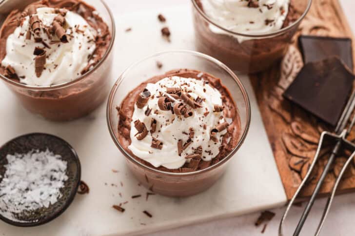 Two small glass dishes filled with an easy chocolate mousse recipe, topped with whipped cream and chocolate shavings.