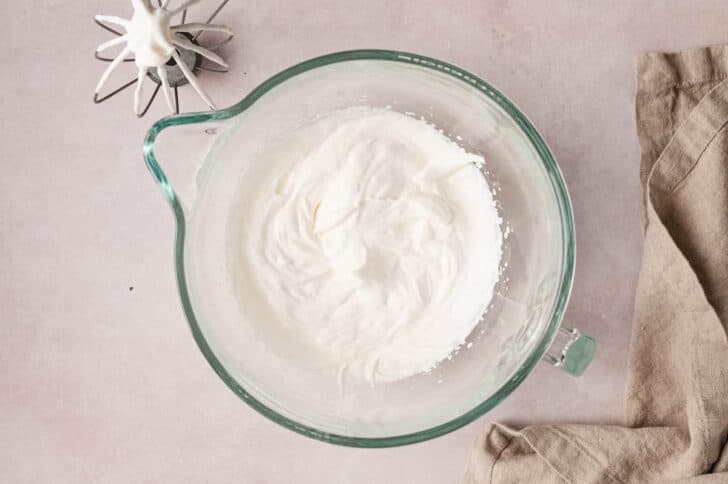 A glass mixer bowl filled with whipped cream.