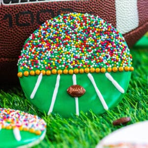 A decorated football cookie leaning up against a football.