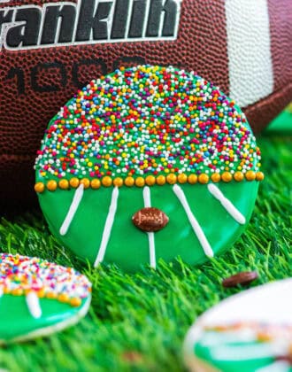 A decorated football cookie leaning up against a football.