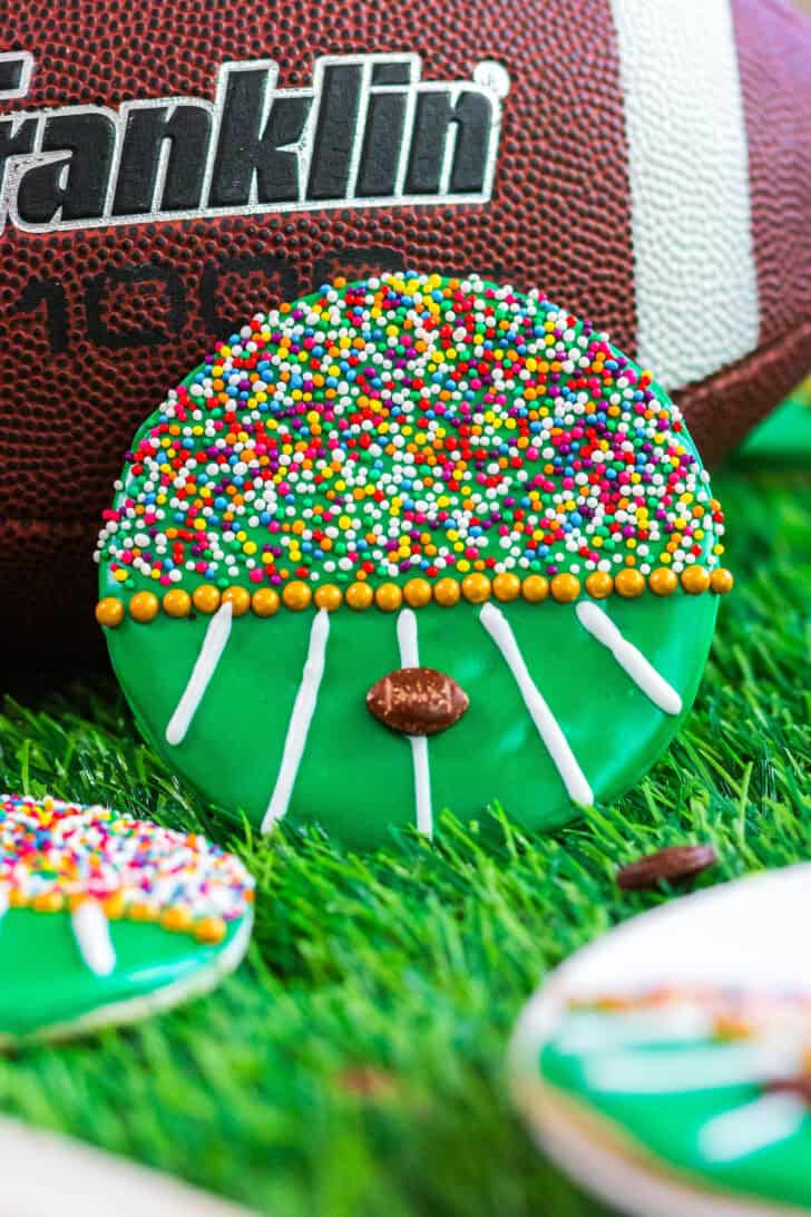 A decorated football cookie leaning up against a football.