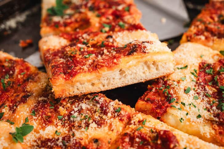 Slices of grandmas pizza piled on a pan.