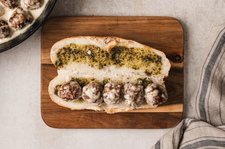 A meatball hoagie on a wooden cutting board.