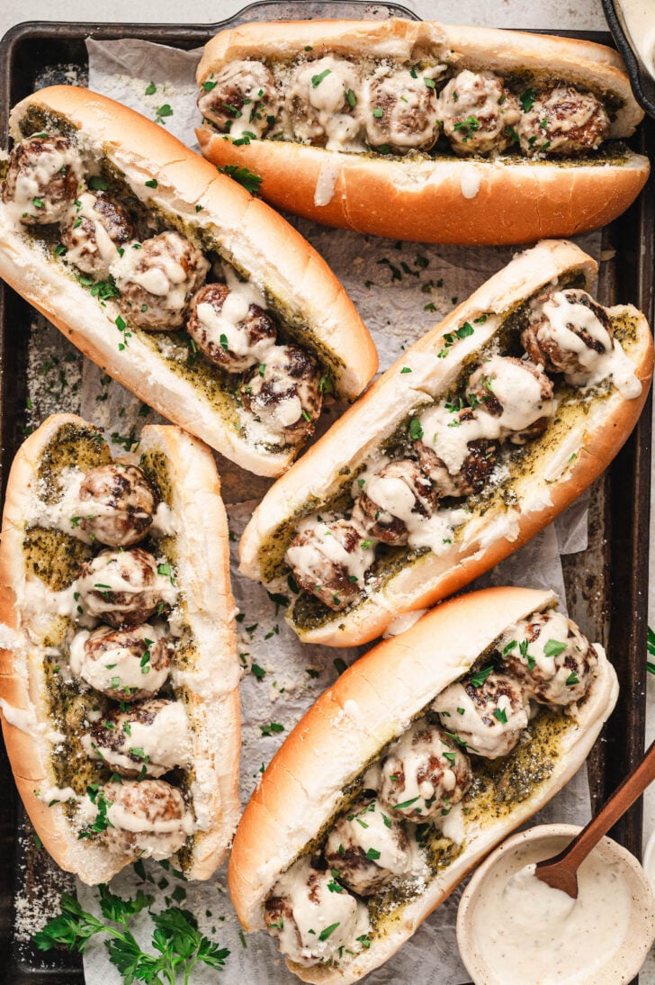 Meatballs subs without marinara on a rimmed baking pan.