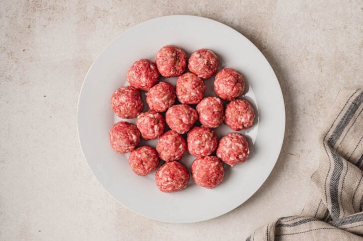 Raw meat balls on a white plate.