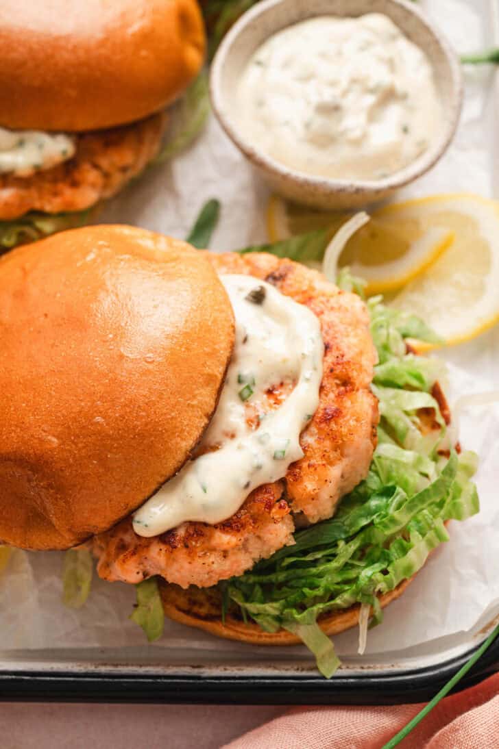 The best salmon burger recipe topped with tartar sauce on a brioche bun.