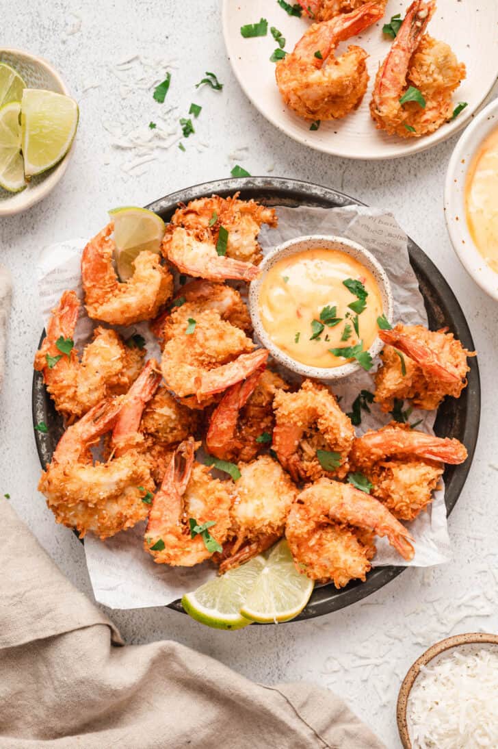 A coconut shrimp recipe being served with an orange dipping sauce.