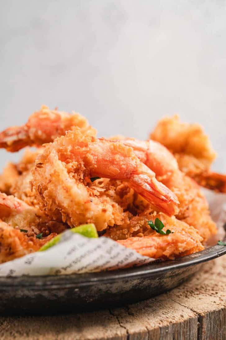 Fried coconut shrimp being served on a metal plate.