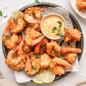 A finished coconut shrimp recipe being served with lime wedges.