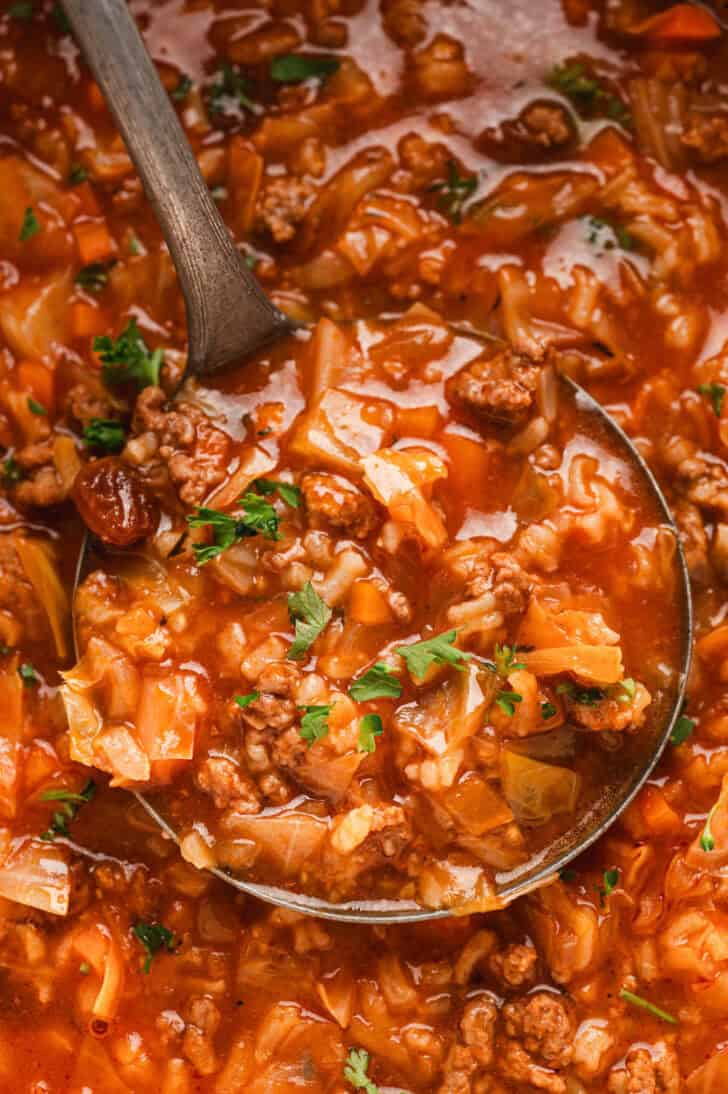 Closeup on a ladle serving a stuffed cabbage soup recipe.