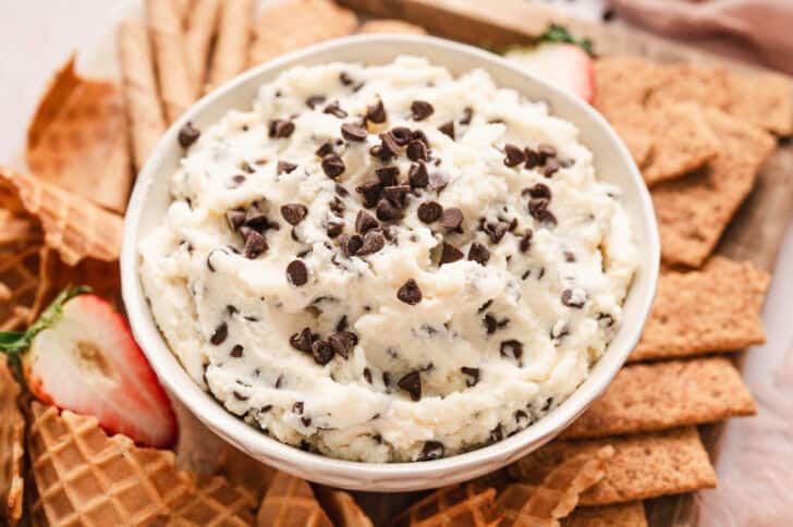 A cannoli dip recipe being served with a variety of sweet crackers and strawberries.