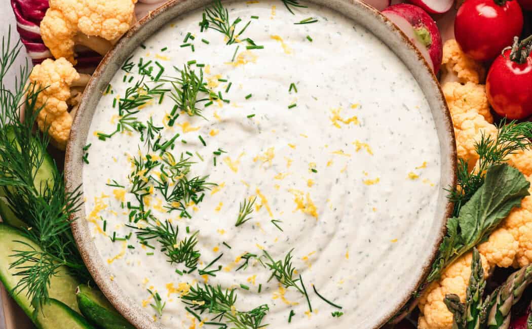 A tray of dill veggie dip and fresh cut vegetables.