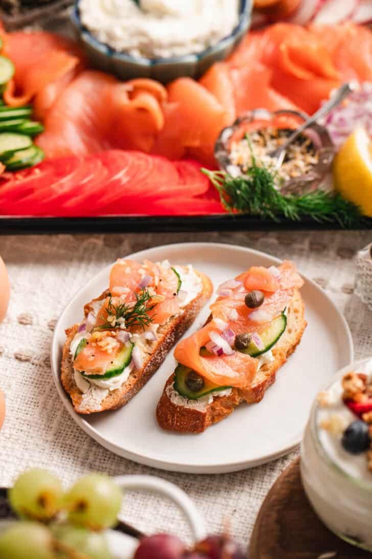 Examples of crostini made from a smoked salmon charcuterie board, on a small white plate.