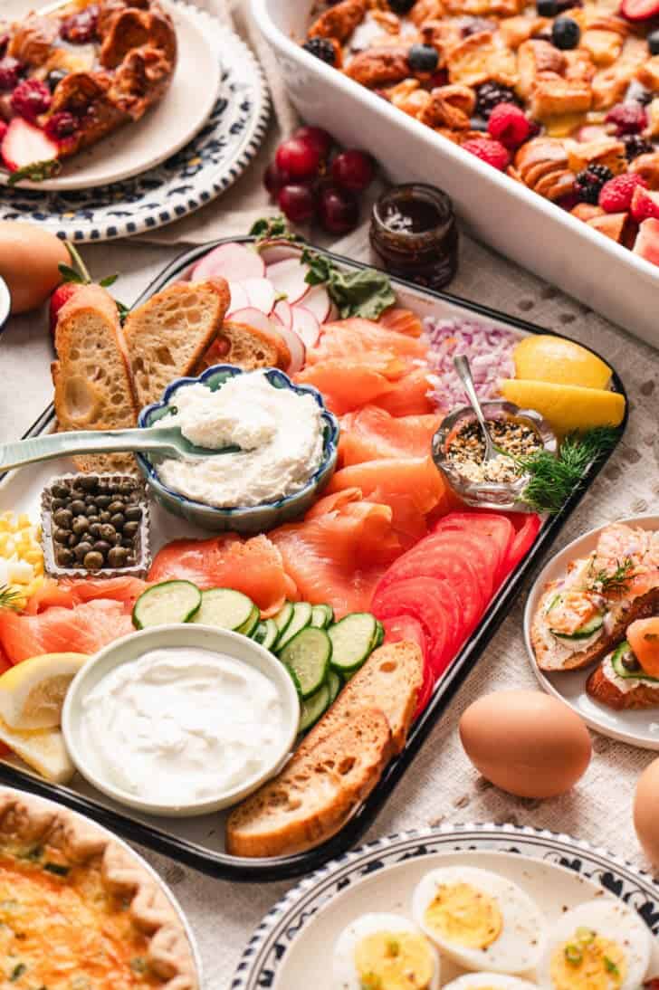 A smoked salmon plate shown as part of a larger brunch spread.