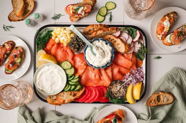 Examples of what to serve with smoked salmon, including crostini made with cream cheese, capers and sliced veggies.