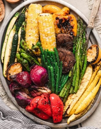 A big platter of the best vegetables to grill, including beans, asparagus, corn, bell peppers, squash, mushrooms, corn and onion.