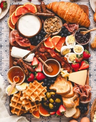 A breakfast charcuterie board on a patterned background.