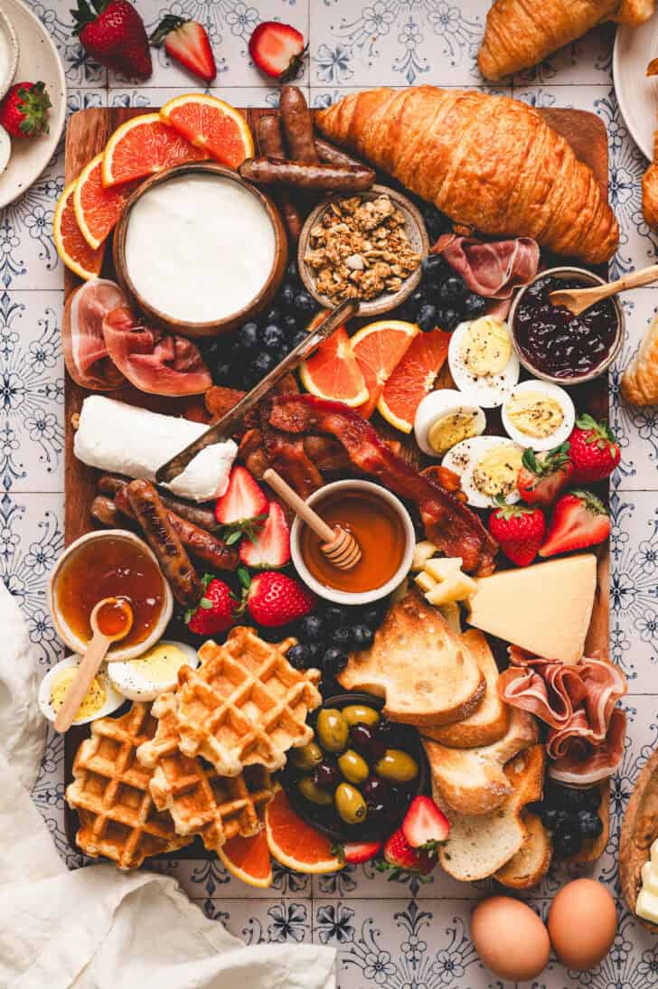 A breakfast charcuterie board on a patterned background.