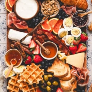 A breakfast charcuterie board on a patterned background.